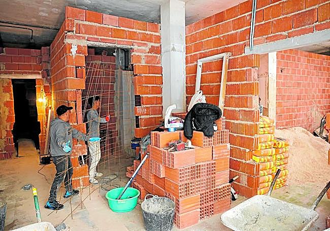 Dos obreros realizan divisiones interiores en un local de Vistalegre, en Murcia, donde irán tres casas.