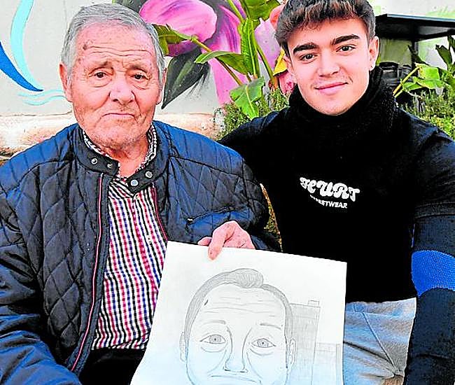 Ramón Ibáñez y Miguel Marín muestran el retrato del mayor en el patio de la residencia.