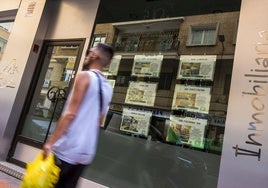 Un joven pasa frente al escaparate de una inmobiliaria en Murcia.