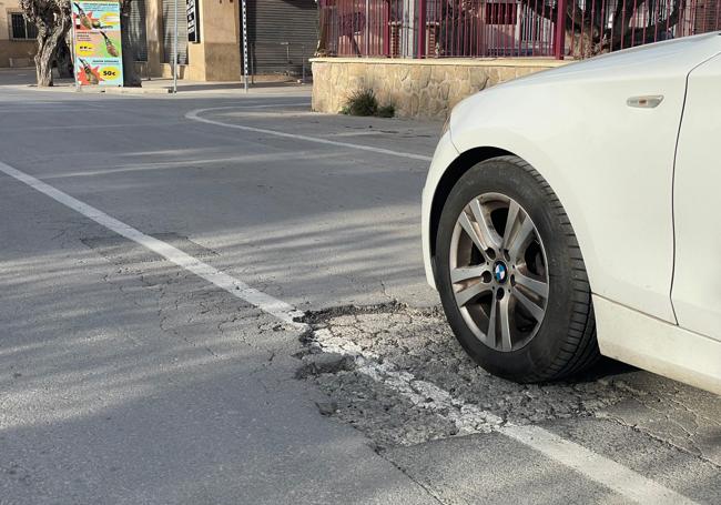 Un coche pasa sobre un socavón en la vereda de Tabala en Alquerías, sobre el que se ha repintado la línea.