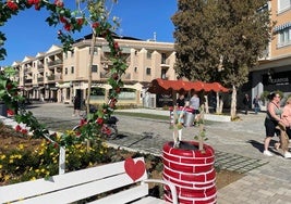 Turistas pasean ante la decoración de San Valentín en la avenida Río Nalón de Los Narejos.