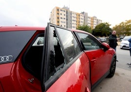 Dos vecinos hablan junto a uno de los vehículos vandalizado el pasado fin de semana junto al residencial Parque Norte de la pedanía murciana de Cabezo de Torres.