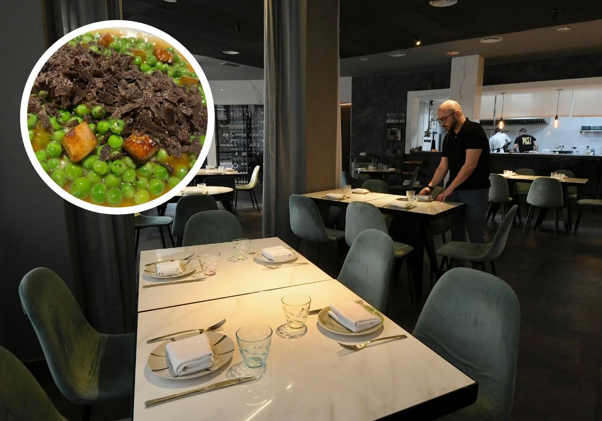 El personal de sala prepara una de las mesas en el comedor, con la cocina abierta al fondo.