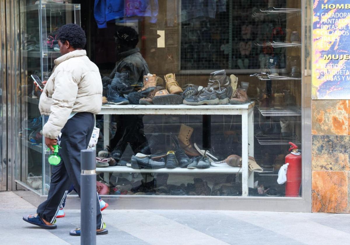 Una tienda de segunda mano con zapatos acumulados en el escaparate.