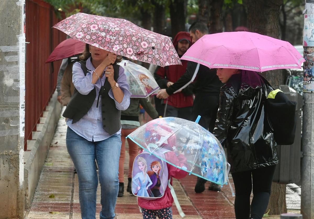 Varias madres recogen a sus hijos del colegio en el barrio de El Ranero en un día de lluvia.