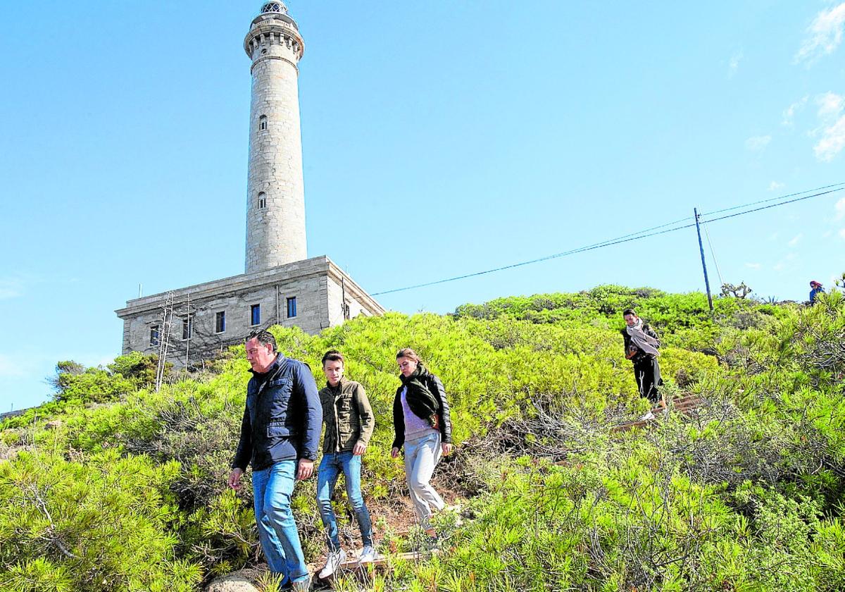 Cuatro excursionistas pasean junto al Faro de Cabo de Palos.