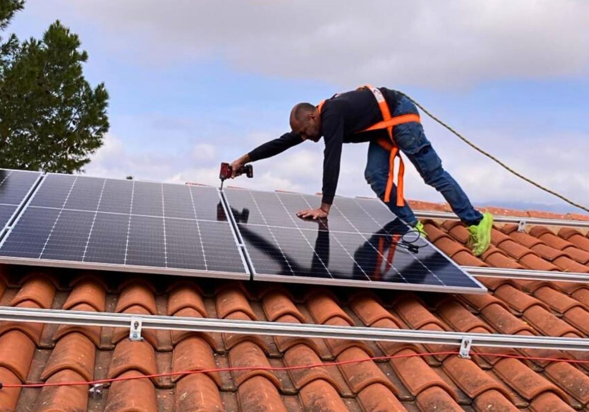 Un operario instala un panel solar en el tejado de un inmueble.