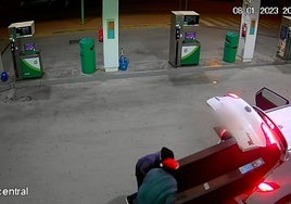 Dos encapuchados, uno de ellos con un gorro de Papá Noel, cargan en un coche una máquina de tabaco robada.