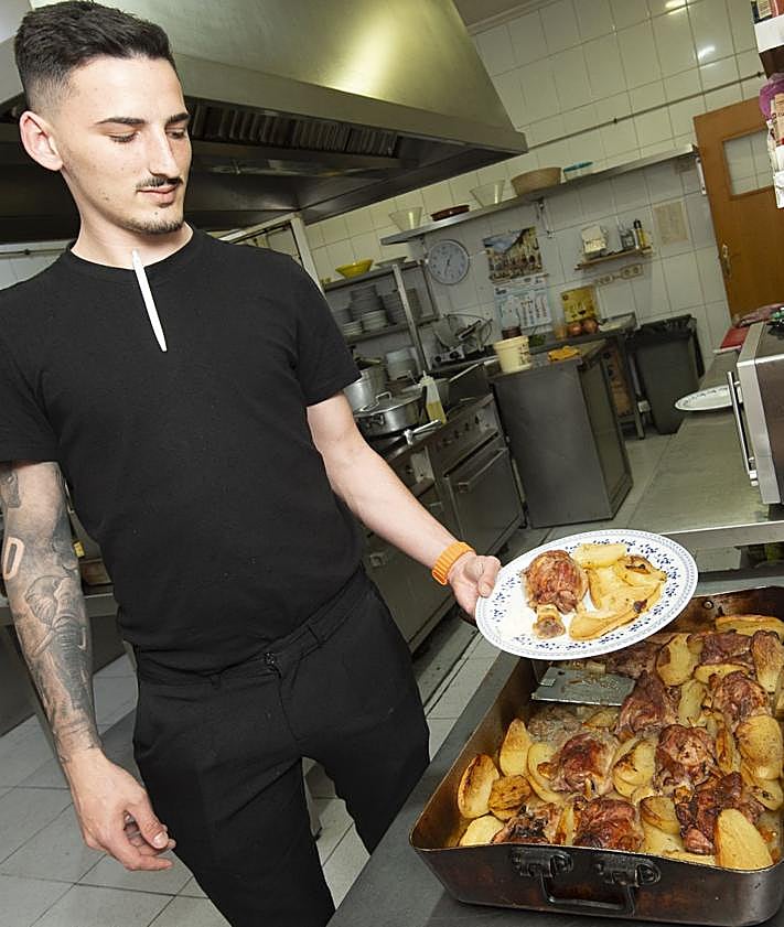 Imagen secundaria 2 - Trabajadores, pizarra con el menú y asado del restaurante Las Palmeras IV.