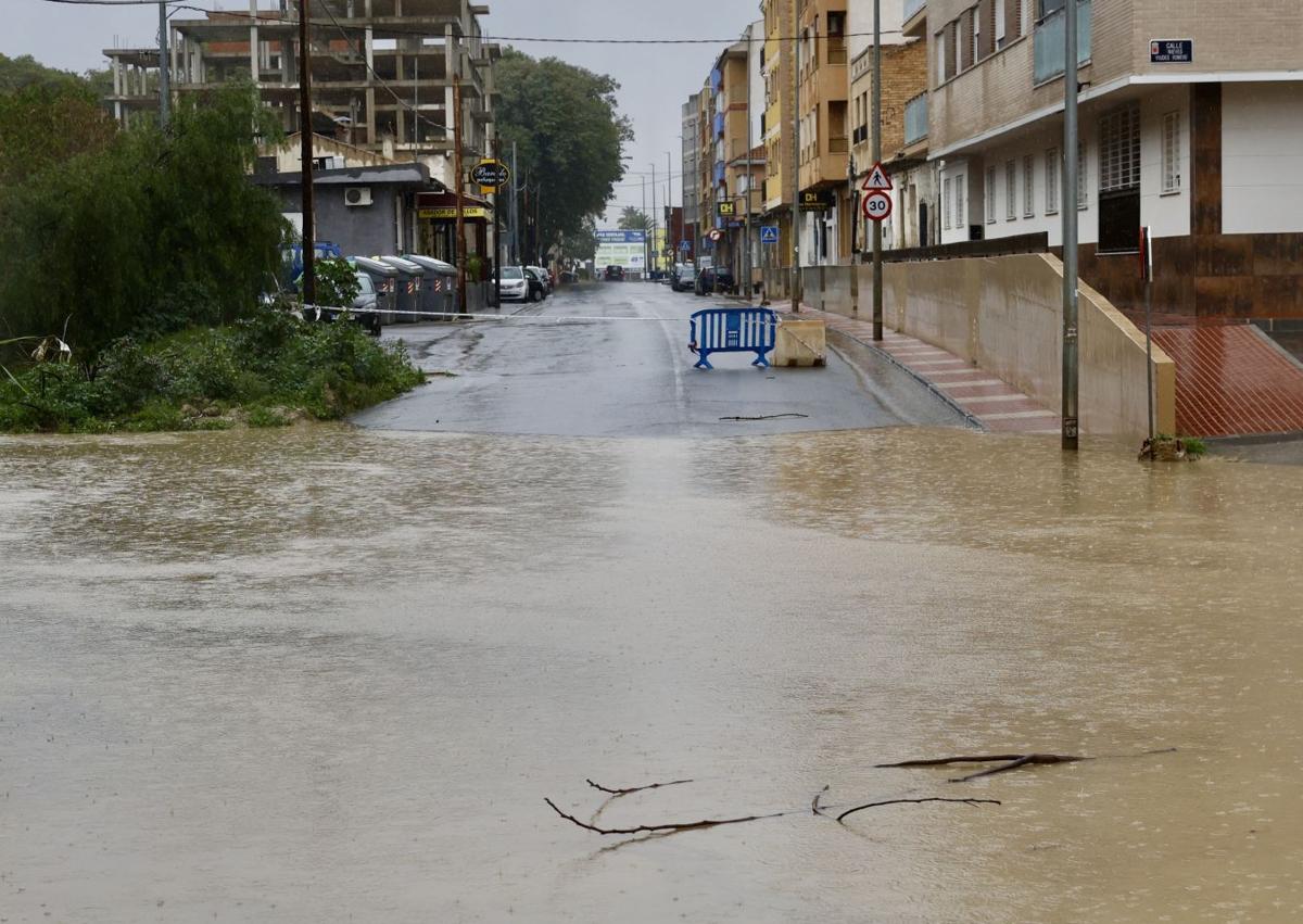 Imagen secundaria 1 - La rambla del Garruchal, desbordada, a su paso por Beniaján, este miércoles.