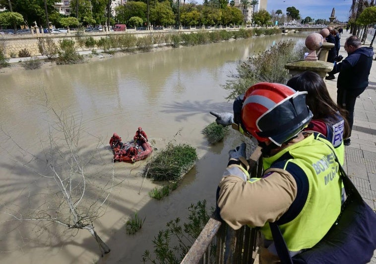 Un bombero señala un punto a sus compañeros en una zódiac, en el dispositivo de búsqueda coordinado por la Policía Nacional.