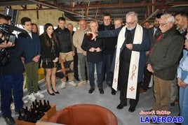 El rector de la basílica verte el vino bendecido por la Vera Cruz en el depósito con la cosecha de este año