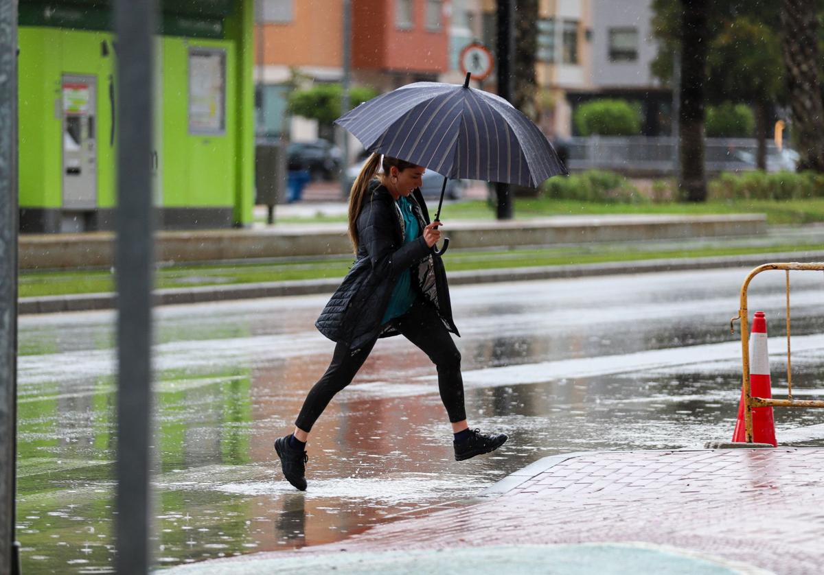 Una mujer camina por Murcia, con paraguas, en un día lluvioso.