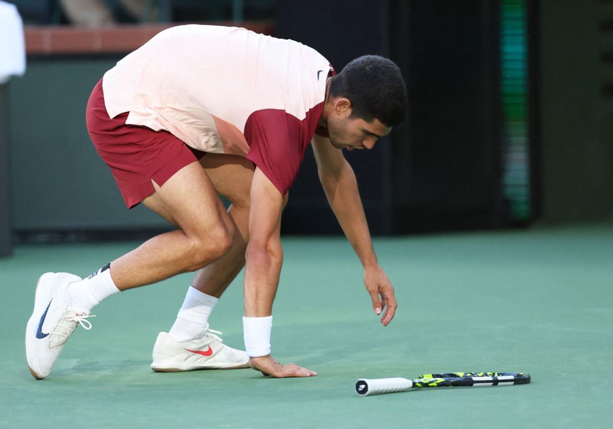 Carlos Alcaraz se agacha para recoger la raqueta tras perder un punto ante Draper en Indian Wells.