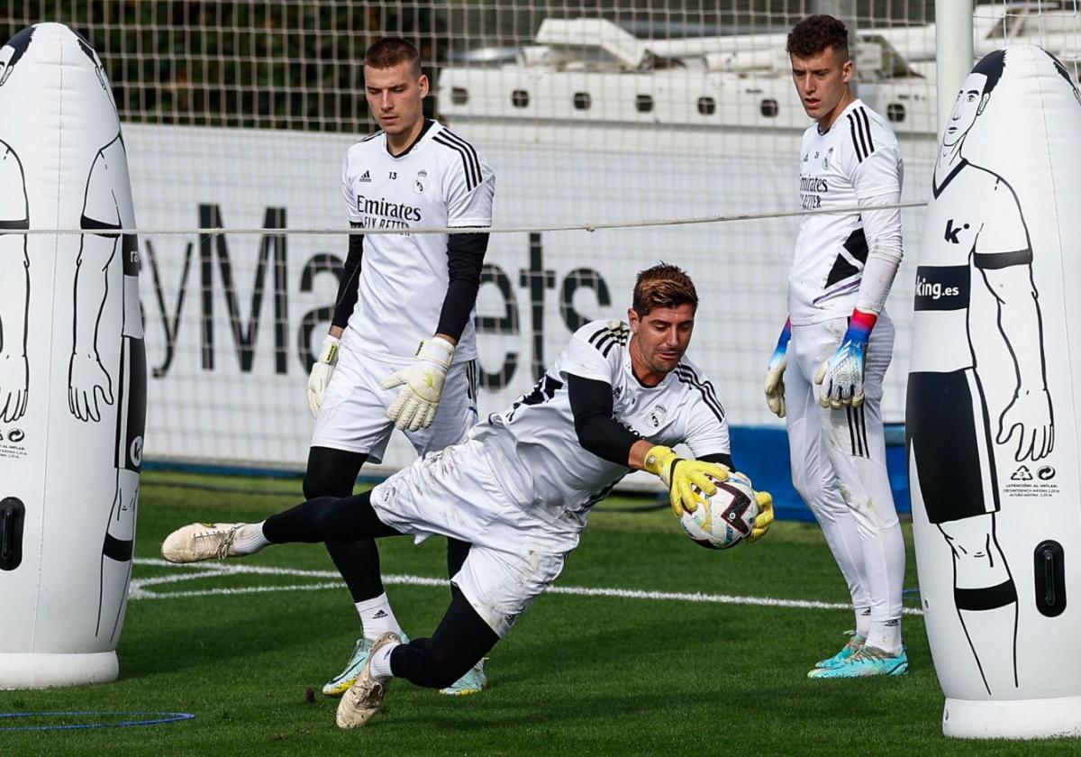 Courtois ataja un balón en un entrenamiento del Real Madrid bajo la atenta mirada de Lunin.