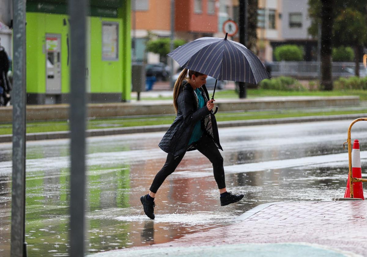 Una mujer se protege de la lluvia con un paraguas, en la zona norte de Murcia.