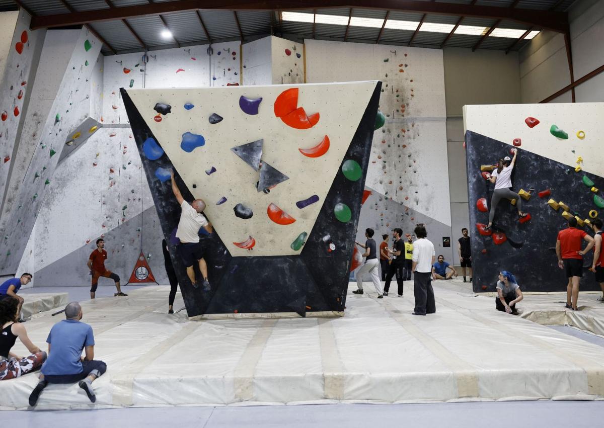 Imagen secundaria 1 - Jóvenes intentan superar un bloque de rocas en el rocódromo La Gatera de Murcia.