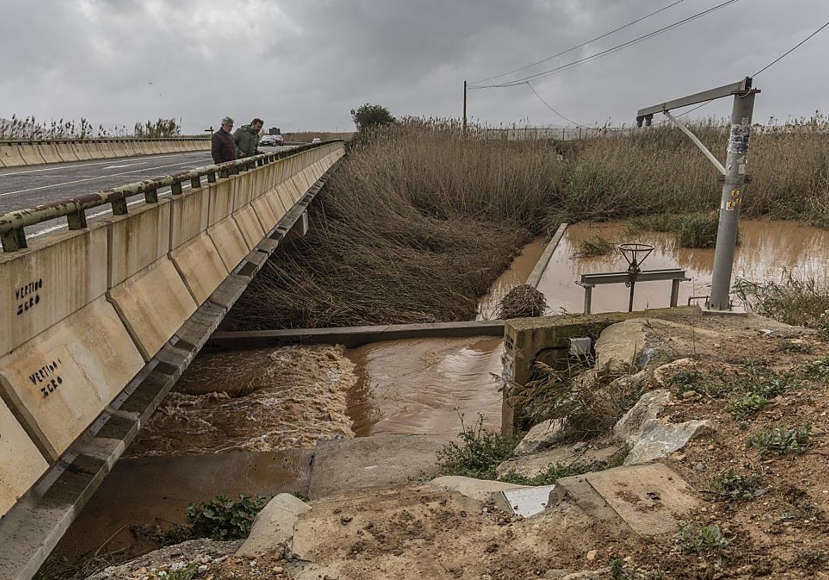 Dos personas contemplan la bajada de agua por la rambla del Albujón tras las primeras grandes lluvias en marzo de este año.