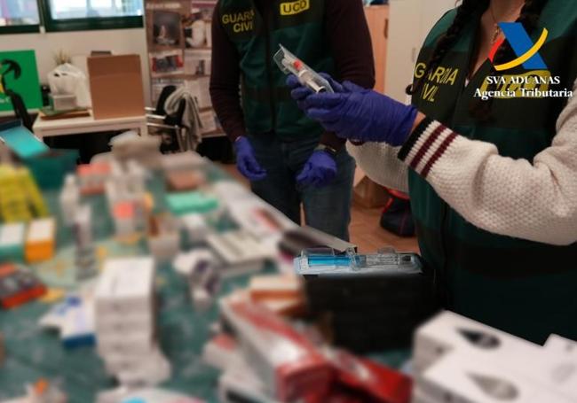 Dos agentes revisan los productos intervenidos importados desde Corea del Sur.