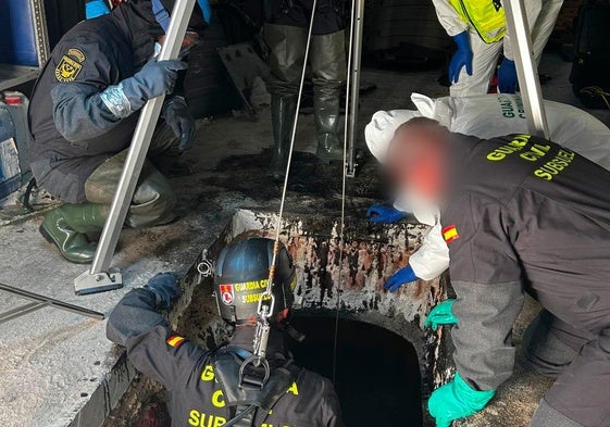 Un agente de la Guardia Civil se introduce en el depósito de aceite donde se encontraron los restos humanos.
