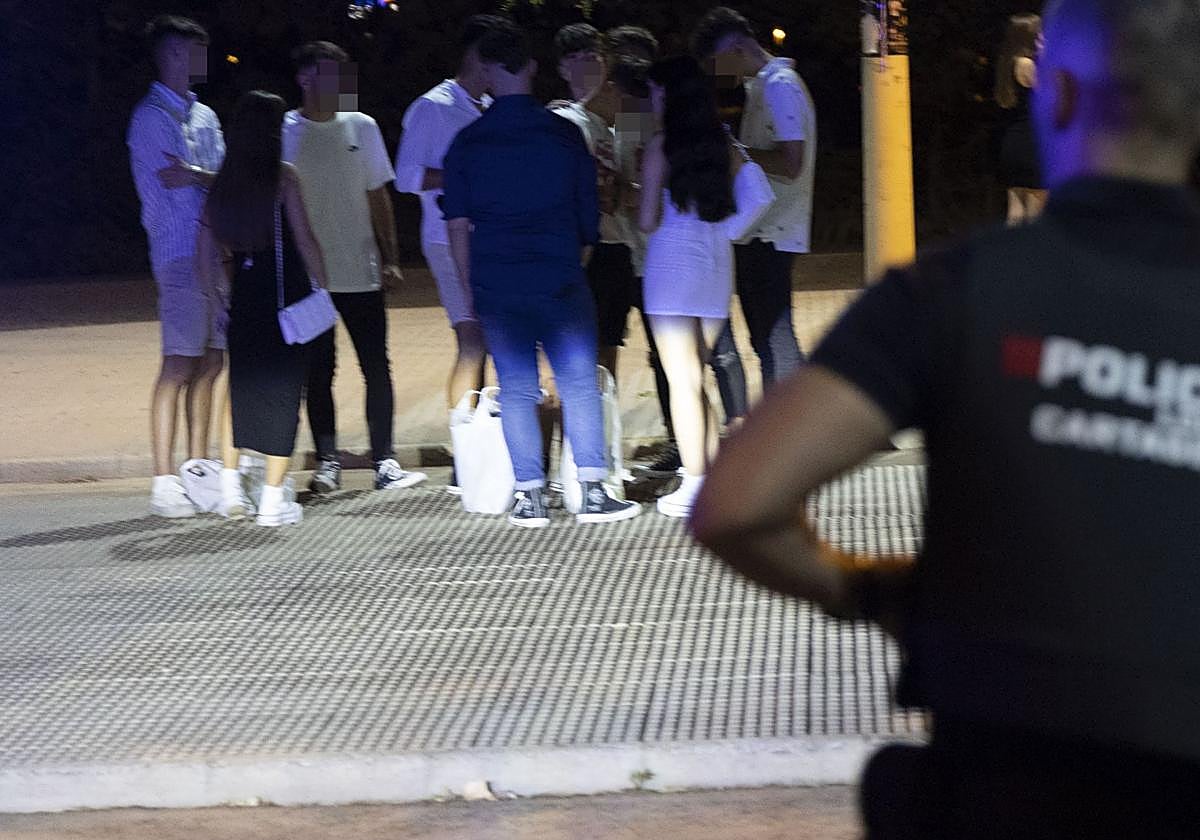 Un policía vigila a unos jóvenes de 'botelleo' en una imagen de archivo.