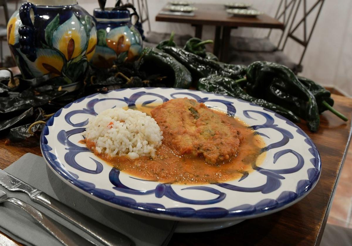 Imagen principal - Chile poblano relleno de queso en salsa de tomate, verdolagas en salsa verde con cerdo y frijoles, y la vitrina de los tequilas.
