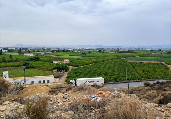 Un camión circula por la vía que une Santomera y El Raal, junto a la huerta, vista desde el monte Balumba.