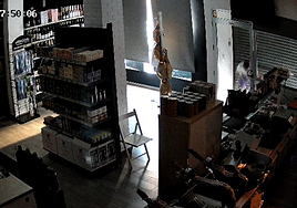 El ladrón rompiendo el cristal del escaparate.