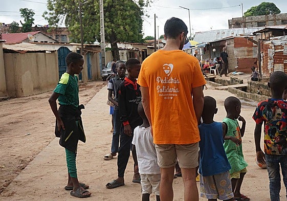 Un voluntario de Pediatría Solidaria juega con unos niños en Faji Kunda, en Gambia, en 2023.