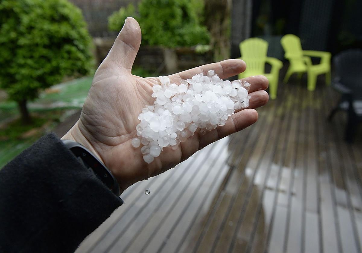 Un hombre muestra el granizo caído en su jardín.