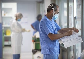 Un sanitario toma notas en el historial de un paciente, en el hospital Reina Sofía.