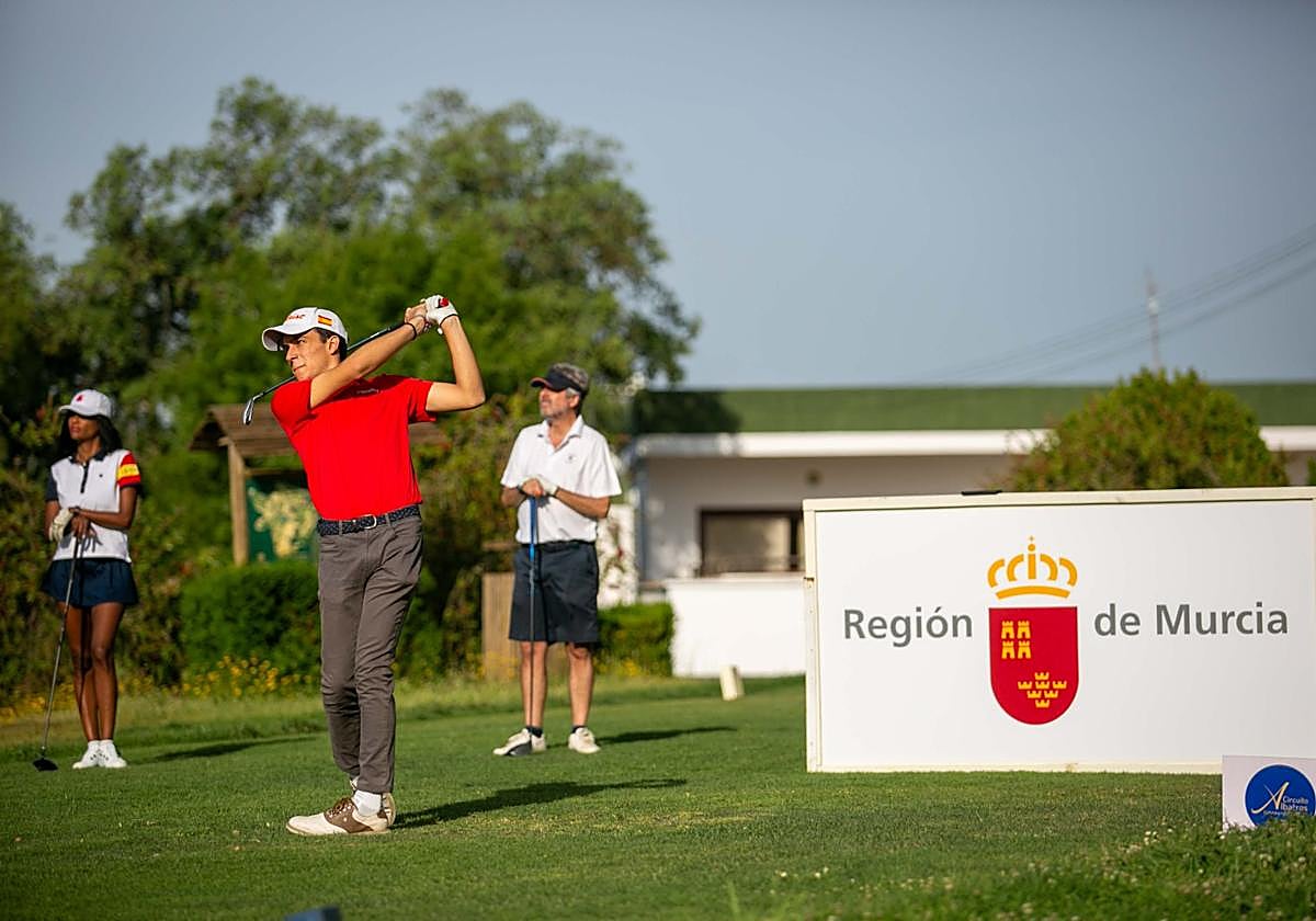 Un jugador en el 'tee' de salida con valla promocional de Destino Región de Murcia.