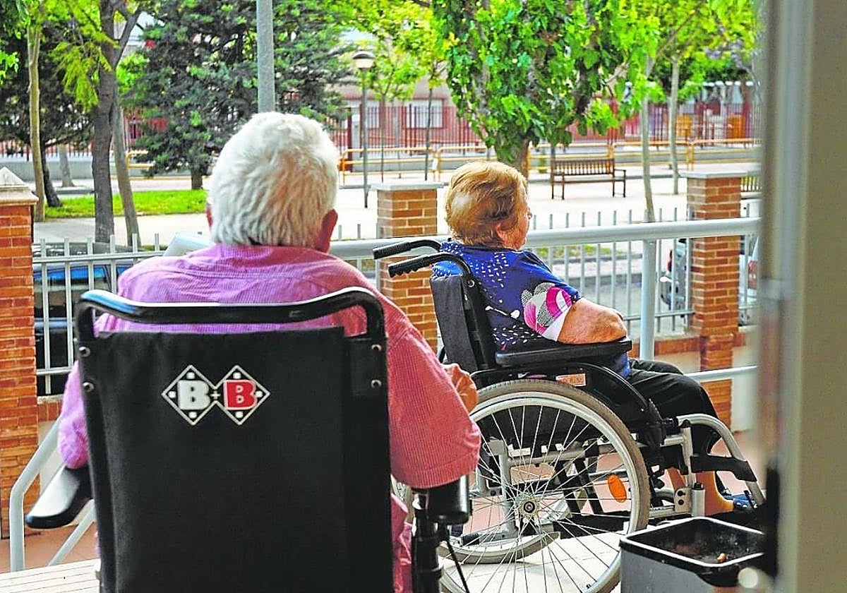 Dos personas mayores salen al exterior de una residencia para tomar el fresco en una imagen de archivo.