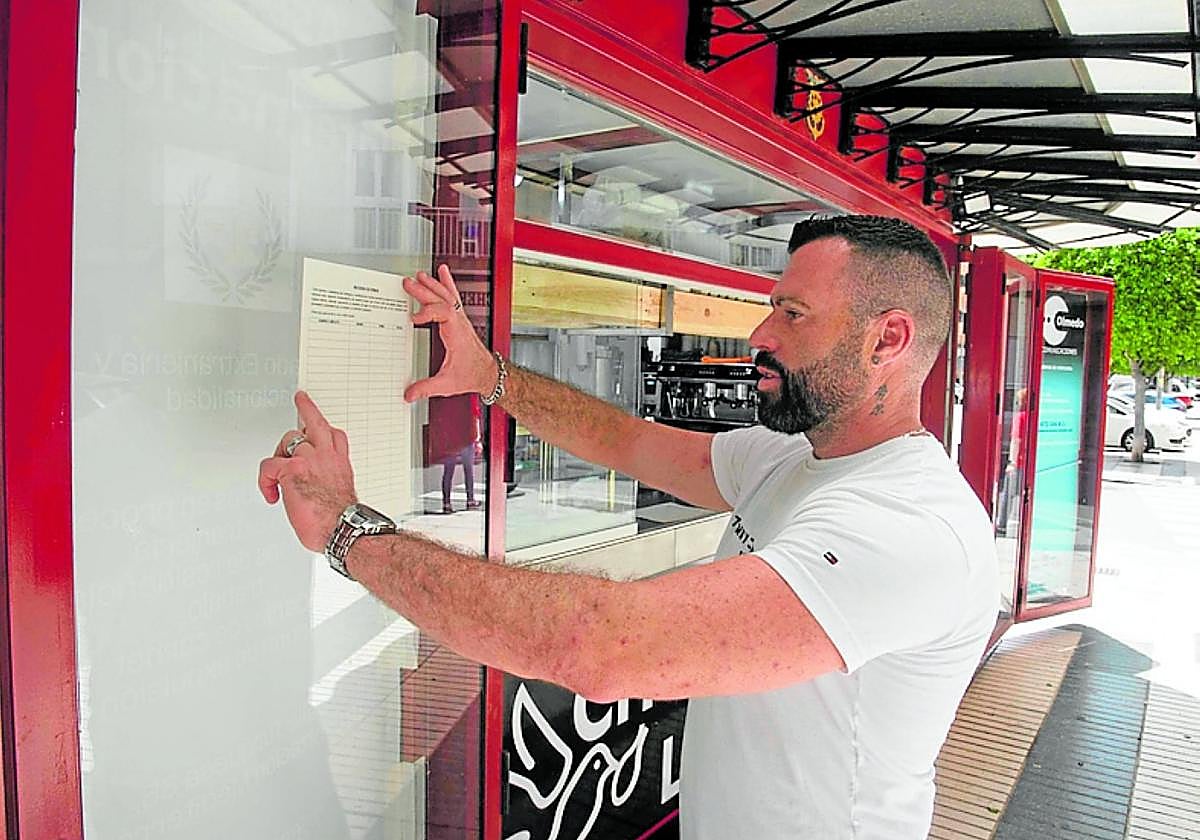 Rodríguez coloca una hoja de firmas en su quiosco.