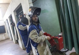 Un alumno del taller de soldadura se pone los guantes.