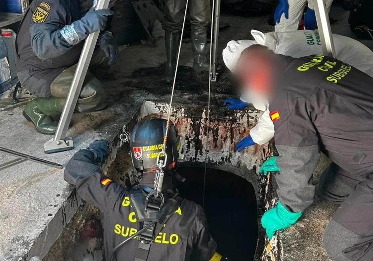 Un agente de la Guardia Civil se introduce en el depósito de aceite donde se encontraron los restos humanos.