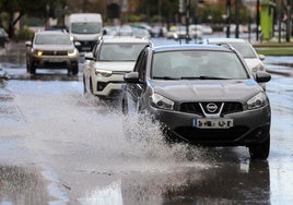 Un coche atraviesa una carretera encharcada tras una tormenta.