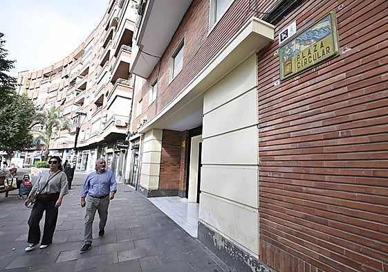 Dos transeúntes pasan junto a la placa con el nombre de la plaza Circular, obra del ceramista Pedro Borja.