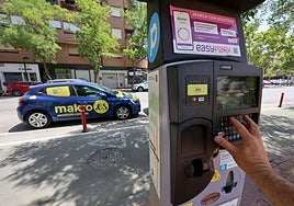 Un usuario sacando un tique en uno de los parquímetros de estacionamiento regulado en la ciudad para las zonas azul y verde.