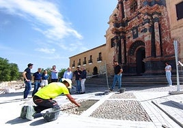 Un operario, junto a técnicos y autoridades, este lunes, durante la visita a las obras en la explanada de la basílica.