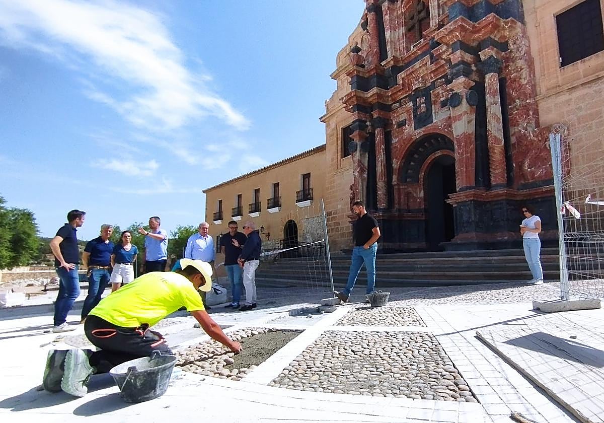 Un operario, junto a técnicos y autoridades, este lunes, durante la visita a las obras en la explanada de la basílica.