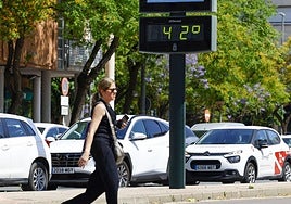Una mujer cruza la calle junto a un termómetro que marca 42 grados en Murcia.
