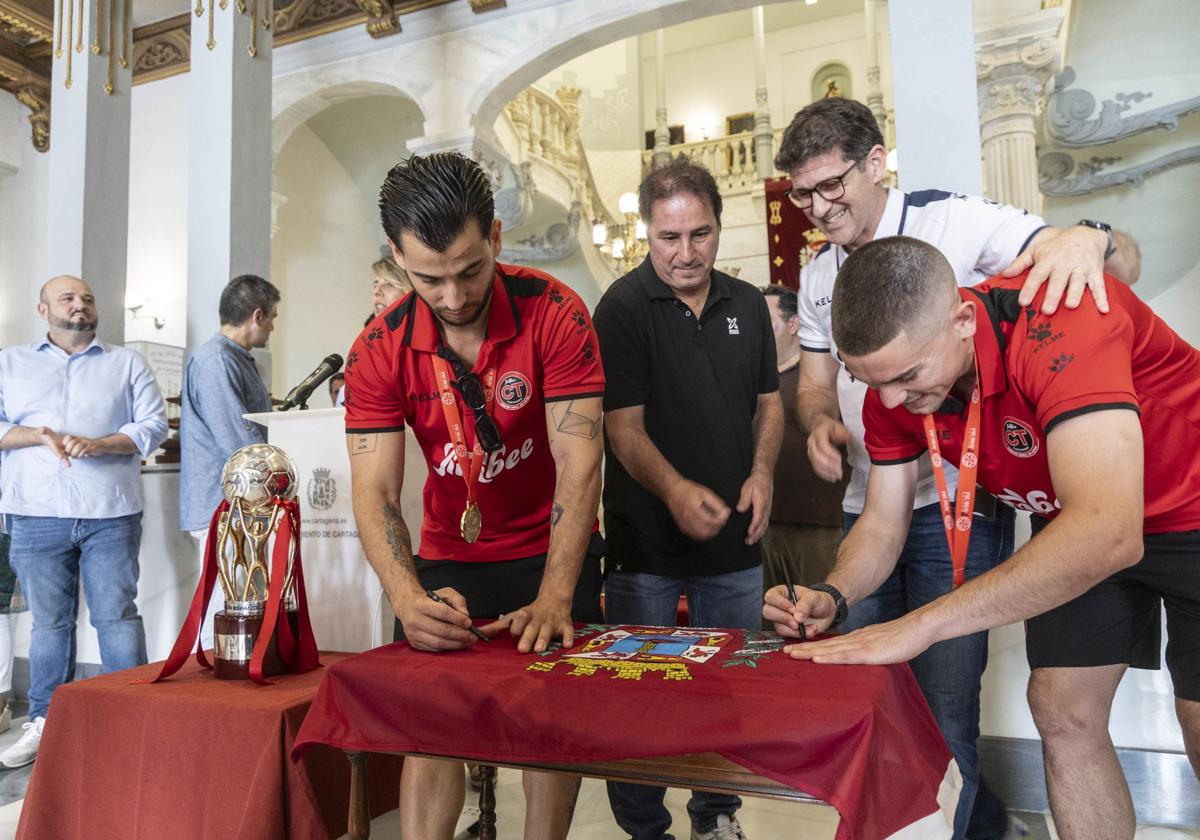 Waltinho, Paulo Roberto, Duda y Mellado firman la bandera de la ciudad, este viernes, con el título de Liga, en la recepción oficial en el Palacio Consistorial.