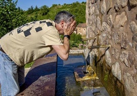 Una persona se refresca en una fuente.