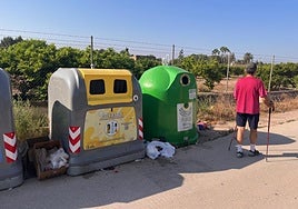 Un vecino camina al lado de contenedores con basura en el suelo.