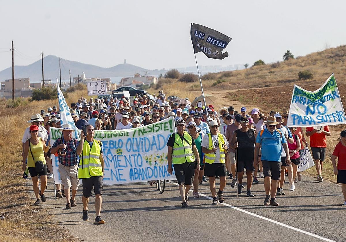 Vecinos de Los Nietos, este domingo, cortan la RM-F54 durante la marcha reivindicativa con pancartas.