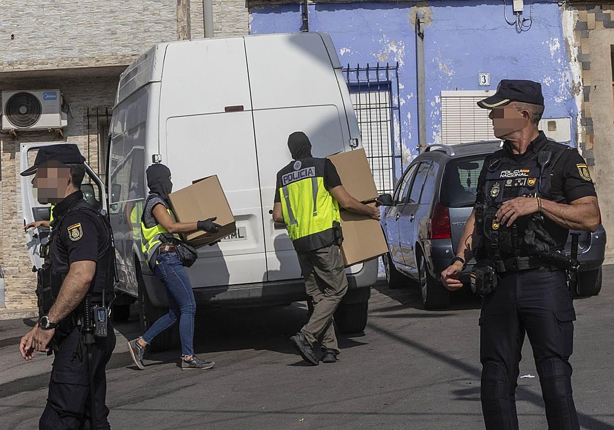 Agentes de la Policía Nacional con pasamontañas descargan cajas en una furgoneta, este martes.