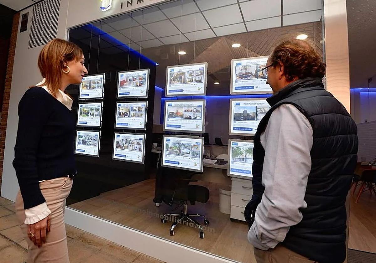 Dos personas frente a una inmobiliaria, en una foto de archivo.