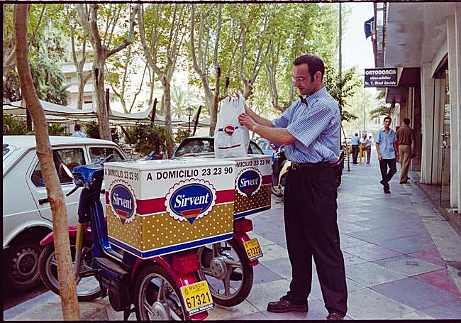 Servicios. El repartidor Julio Tortosa prepara su moto en el paseo Alfonso X de Murcia para realizar uno de los pedidos de la tarde (1999).