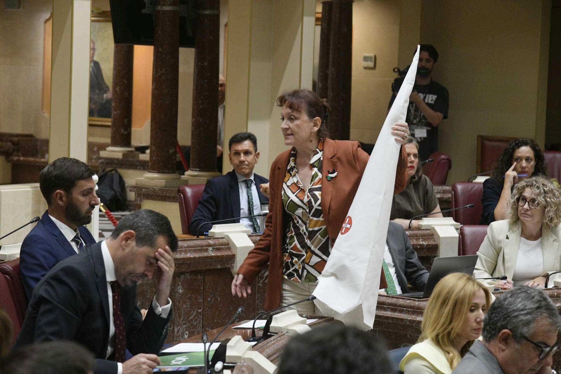 María Marín coloca un capirote del Ku Klux Klan en el escaño de Antelo.